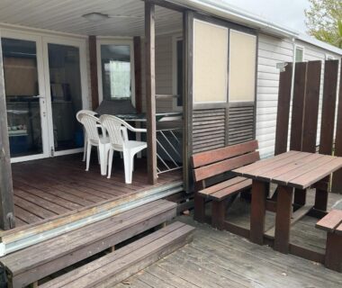 Terrasse et coin repas en bois avec chaises et bancs du camping Loyoda