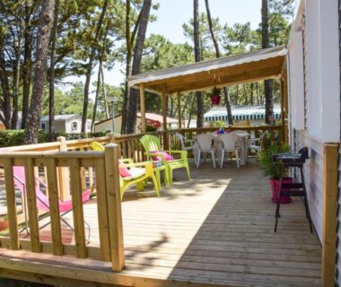Terrasse en bois avec chaises colorées et table du Camping maeva Club Les Préveils