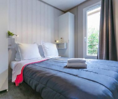 Chambre double avec lit et fenêtre au camping maeva Escapades Colomba