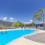 Piscine extérieure avec transats et palmiers au Camping maeva Escapades Colomba