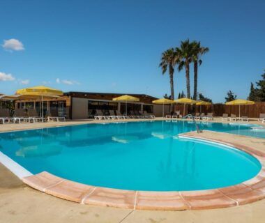 Piscine extérieure avec parasols et palmiers au Camping maeva Escapades Les Cottages de Perpignan