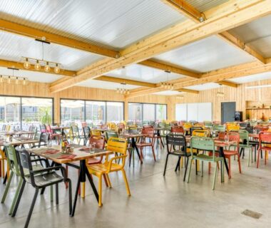 Salle à manger intérieure avec tables et chaises colorées au Camping maeva Escapades Les Cottages de Perpignan