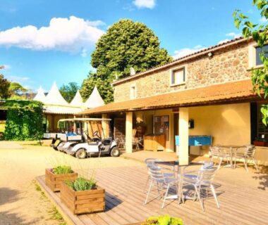 Terrasse extérieure avec tables et chaises devant le bâtiment au Camping maeva Escapades Ludo Parc