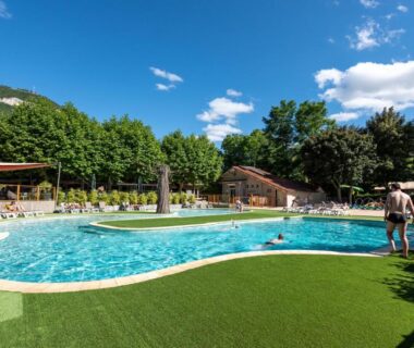 Piscine extérieure entourée de transats au Camping maeva Escapades Millau Plage