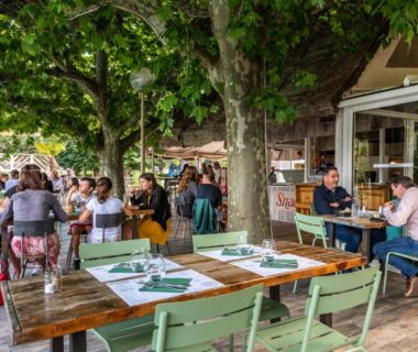 Terrasse ombragée avec tables et convives au Camping maeva Escapades Millau Plage