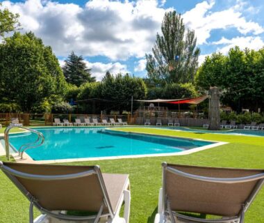 Piscine extérieure avec chaises longues et pelouse au Camping maeva Escapades Millau Plage