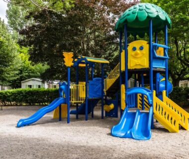 Aire de jeux avec toboggans bleus et jaunes au Camping maeva Escapades Millau Plage