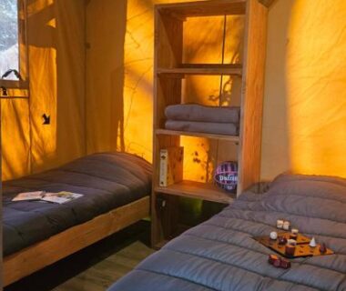 Intérieur de tente avec deux lits et lanterne au Camping maeva Respire La Serre