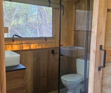 Salle de bain en bois avec douche vitrée et WC au Camping maeva Respire La Serre