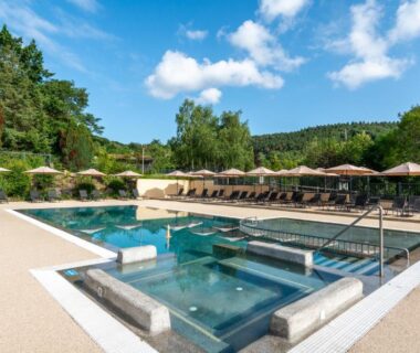 Piscine extérieure avec solarium et parasols au Camping maeva Respire La Serre