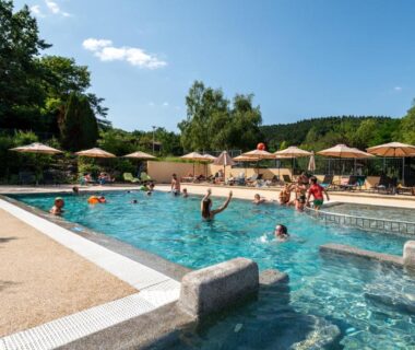Piscine extérieure avec nageurs et parasols au camping maeva Respire La Serre