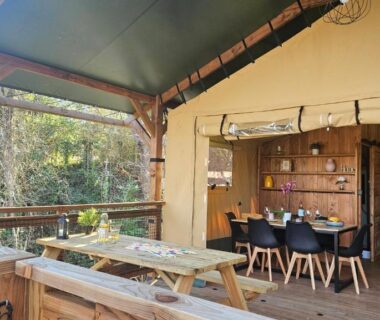 Terrasse en bois couverte avec table et chaises au camping maeva Respire La Serre