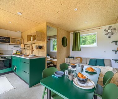 Intérieur du mobil-home avec coin cuisine et table dressée au Camping maeva Respire de La Croze