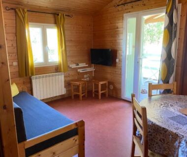 Intérieur salon avec canapé et coin repas dans le Camping maeva Respire de La Croze