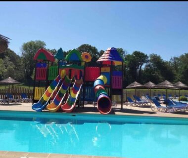 Piscine extérieure avec toboggans colorés et parasols au Camping paradis