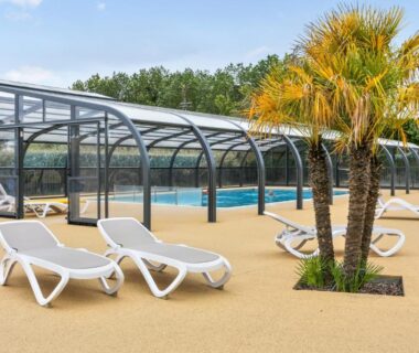 Solarium et piscine couverte avec chaises longues au Camping paradis les pins