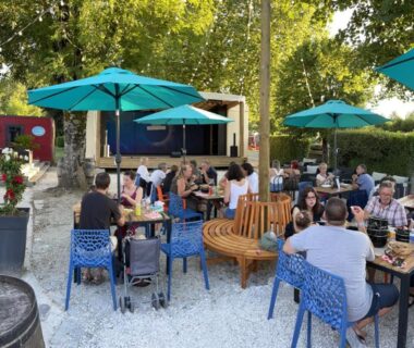 Terrasse extérieure avec parasols, tables et convives au Camping paradis les pins