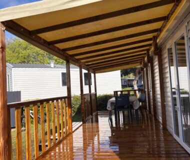Terrasse couverte en bois avec table et chaises au Camping Siblu
