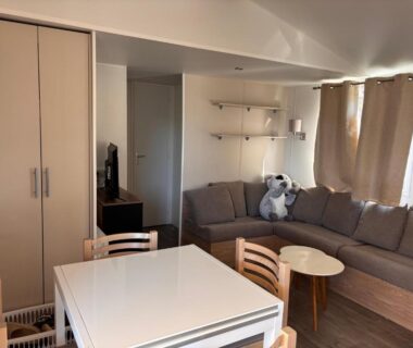 Salon avec canapé et coin repas dans le mobil-home du Camping siblu