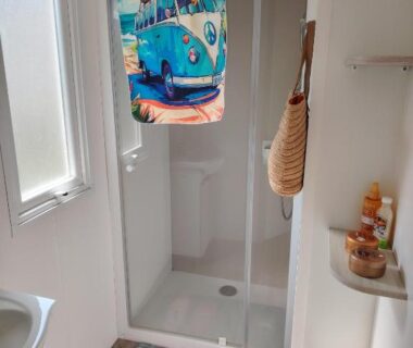 Salle de bain avec cabine de douche et serviette motif van au Cap du Roc