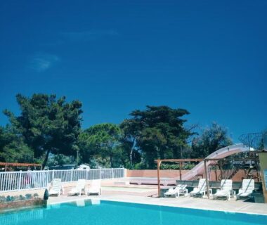 Bord de piscine avec transats parasol et végétation au camping Cap du Roc