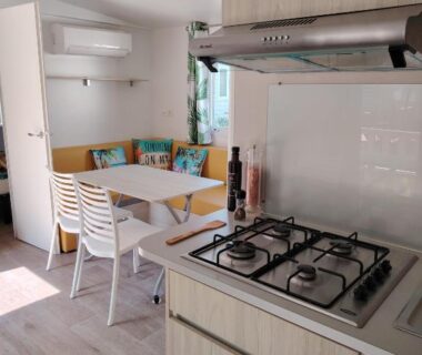 Intérieur du mobil-home avec coin cuisine et banquette au camping Cap du Roc