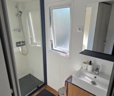 Salle de bain avec douche, lavabo et fenêtre dans le Cap'Océan Lodge