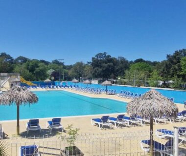 Piscine extérieure avec transats et paillotes au Cap'Océan Lodge