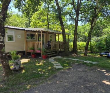 Mobil-home avec terrasse ombragée sous les arbres au Cap'Océan Lodge