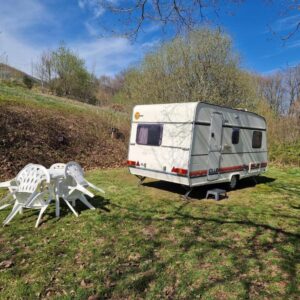 Prairie avec caravane et salon de jardin au Caravan Lara Camping La Foret du Morvan