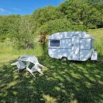 Caravane posée sur pelouse avec table et chaises au Camping Caravan Miekie La Foret du Morvan