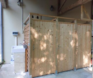Sanitaires avec cabines en bois et lavabo dans le camping Caravane La Clairière