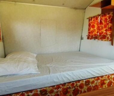 Intérieur de caravane avec lit et rideaux floraux dans la Caravane vintage