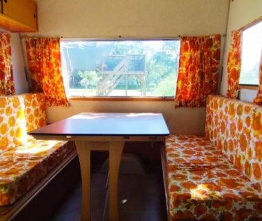 Intérieur avec banquettes fleuries et table dans la Caravane vintage