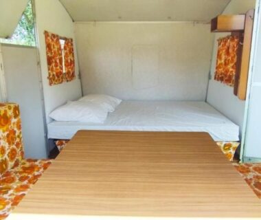Intérieur de caravane avec banquettes fleuries table et lits dans la Caravane vintage
