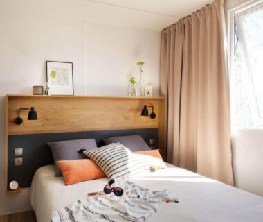 Chambre avec lit double, coussins et fenêtre au Carazur Mobilhomes Camping Fréjus