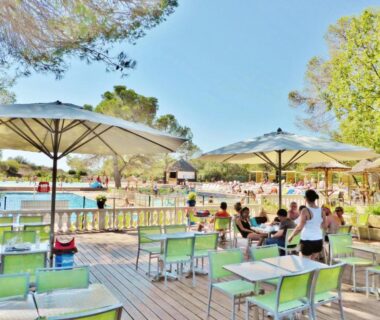 Terrasse au bord de la piscine avec parasols et chaises au Carazur Mobilhomes Camping Fréjus
