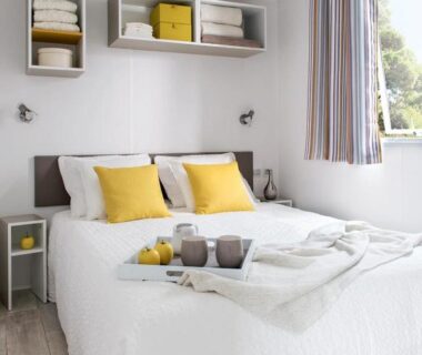 Chambre double lumineuse avec coussins jaunes dans le Carazur Mobilhomes Camping Fréjus