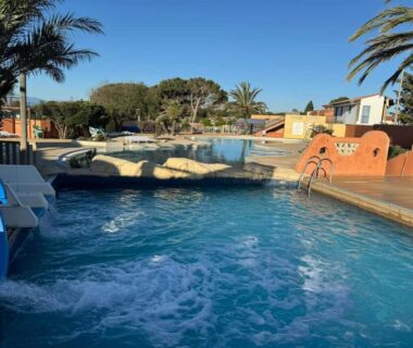 Piscine extérieure avec toboggan et palmiers au camping Casa Luisa Mobil Home