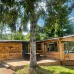 Terrasse en bois et façade sous arbre au Chalet 9 personnes, piscine, terrasse