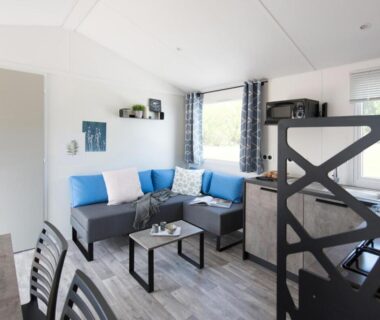 Salon lumineux avec canapé d'angle et kitchenette dans le Chalet Bord de Mer