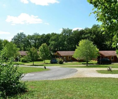 Allée herbeuse et chalets en bois dans la verdure au Chalet Cahors 4 pers