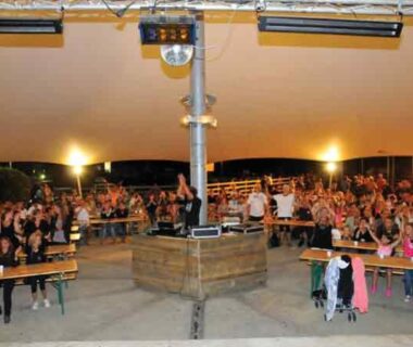 Sous chapiteau soirée conviviale avec bancs et public au Chalet Camping Les Vignes