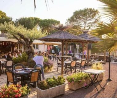 Terrasse extérieure avec tables et parasols au camping Chalet Coco