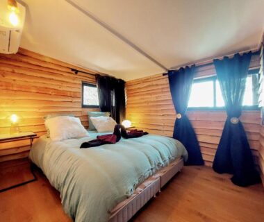 Chambre en bois avec lit double et fenêtres dans le Chalet Oasis et vue mer proxi circuit Paul Ricard