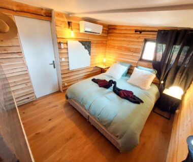 Chambre en bois avec lit double et lampes dans le chalet Oasis et vue mer
