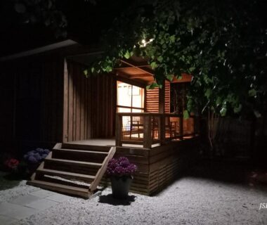 Terrasse en bois éclairée avec marches et pots de fleurs au Chalet Zen