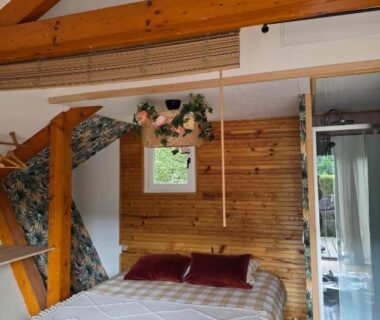 Chambre mansardée avec lit et poutres apparentes dans le Chalet avec piscine 2C