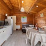 Intérieur de chalet en bois avec coin cuisine et table à manger du Chalet bois 8 Domaine Les Epinettes
