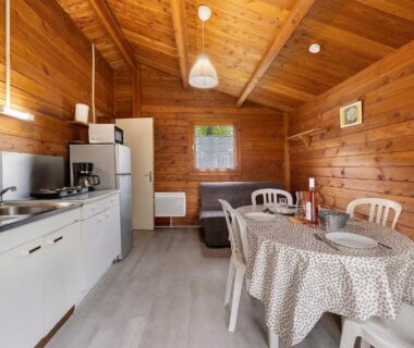 Intérieur de chalet en bois avec coin cuisine et table à manger du Chalet bois 8 Domaine Les Epinettes